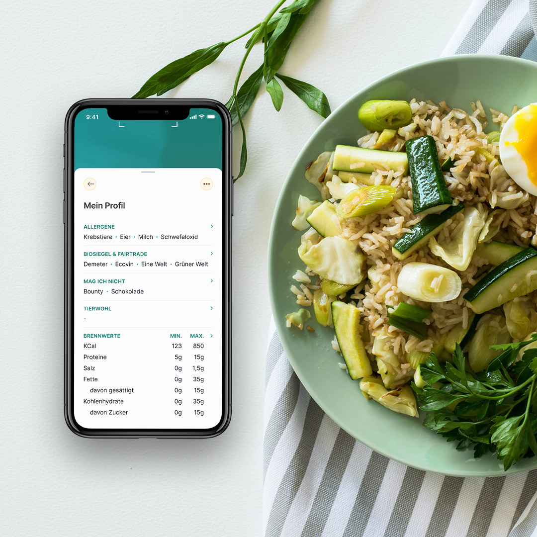 In der SoVi App ist die Profil Seite geöffnet. Das Smartphone liegt auf einem Tisch mit Essen. 