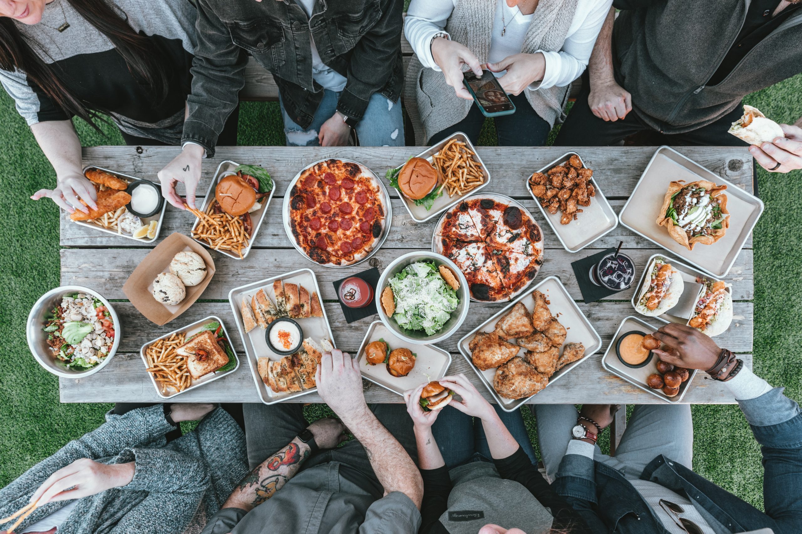 Bild von gedecktem Tisch mit deftigen Speisen und essenden Menschen
