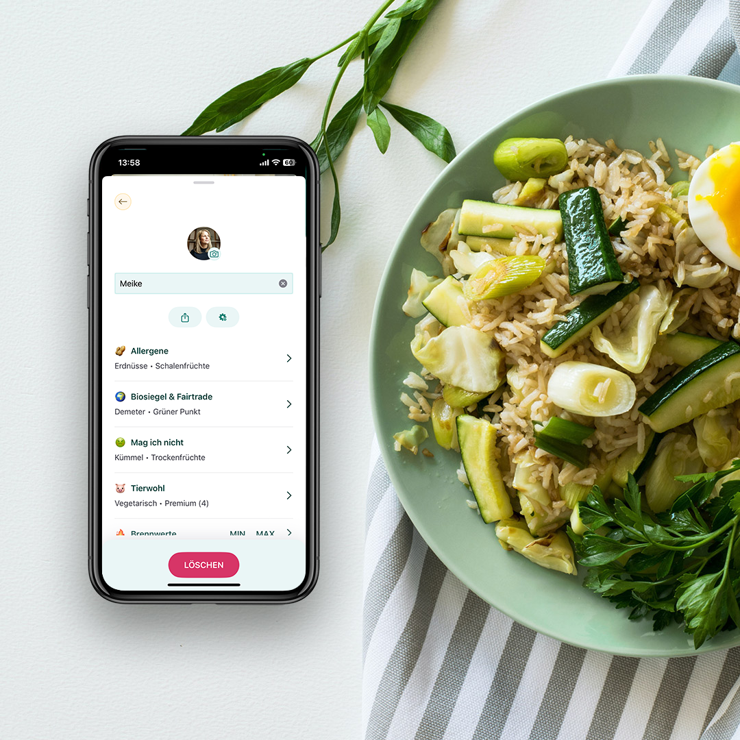 In der SoVi App ist die Profil Seite geöffnet. Das Smartphone liegt auf einem Tisch mit Essen. 
